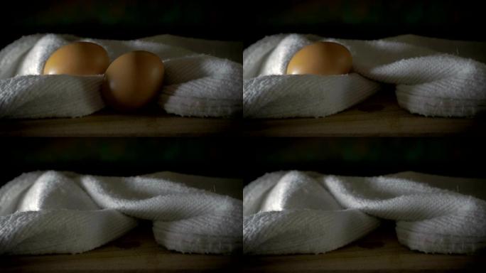 一只手用棉布从木制砧板上捡起棕色鸡蛋