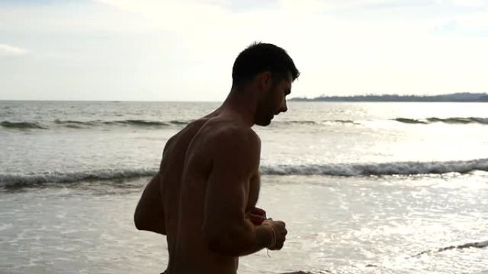 年轻的运动型男子沿着海边奔跑。运动帅哥在美丽的海景背景下慢跑。在海边锻炼的男运动员。健康积极生活方式