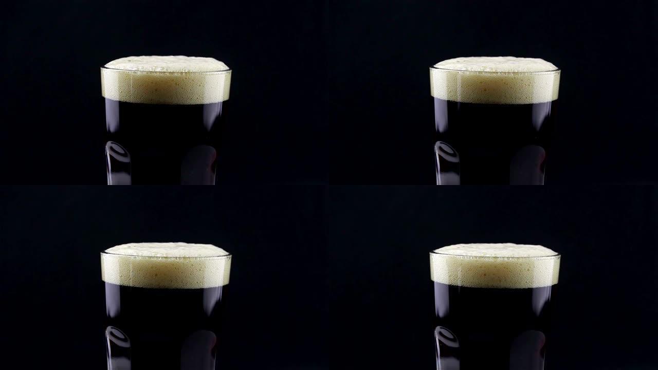 酒保将黑啤酒从瓶子倒入玻璃杯中。一个男人在杯子里装满黑啤酒。