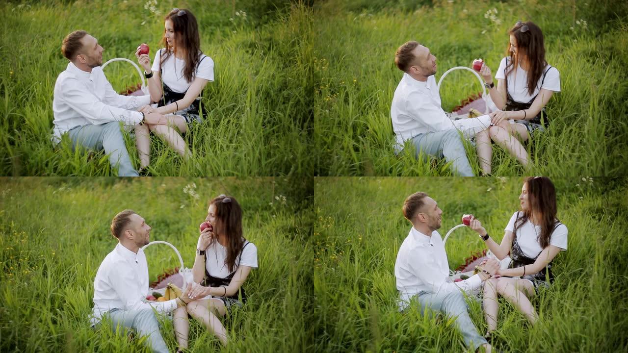 情侣坐在公园的草地上吃苹果。
