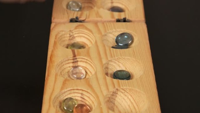 木制mangala游戏，mangala游戏板和玻璃弹珠，黑色背景