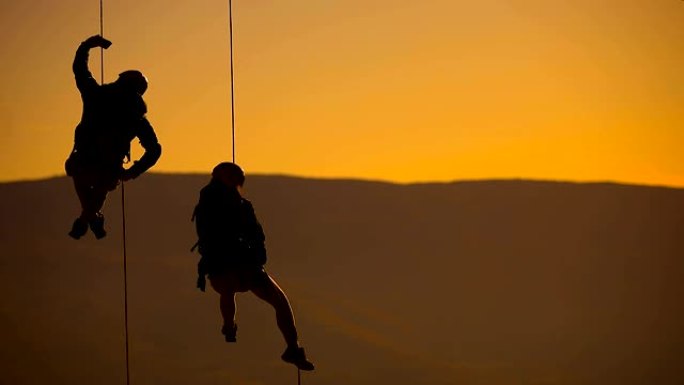 夫妻在绳子上用智能手机拍照。日落登顶的登山队
