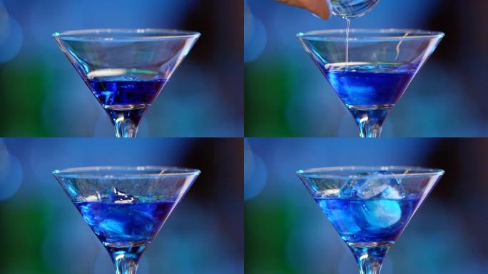 专业酒保用冰装饰蓝色鸡尾酒。调酒师在散焦的背景下准备鸡尾酒，然后倒入并提供鸡尾酒。酒保准备五颜六色的