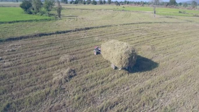 在田野里飞过一辆满载干草的小型拖拉机