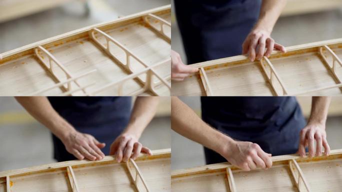 跟踪无法识别的木匠的左特写手，在木工车间的工作台上制作木制的船模型