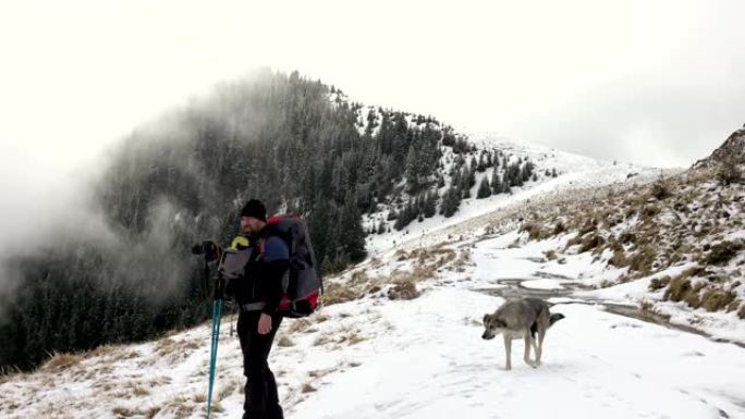 摄影师带着背包走在山脊上，上面覆盖着深雪
