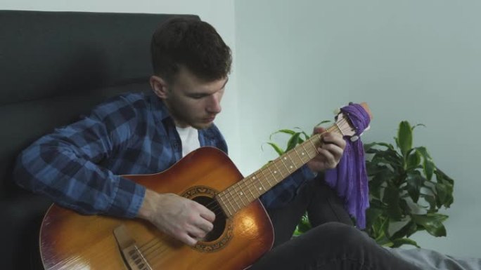年轻的音乐家吉他手在家用吉他手指演奏性感的慢民谣，为音乐会练习。
