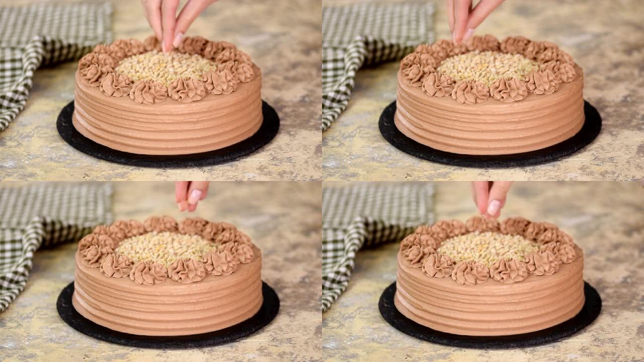 在巧克力海绵蛋糕的奶油上撒坚果的特写镜头。贝克用坚果装饰巧克力蛋糕。