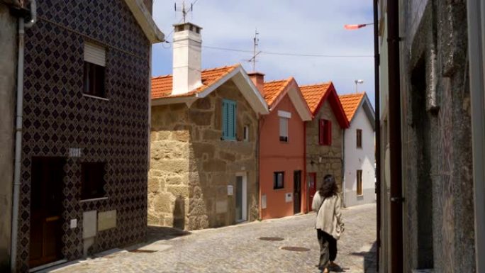 女人走在Vila Cha五颜六色的房子街，在葡萄牙