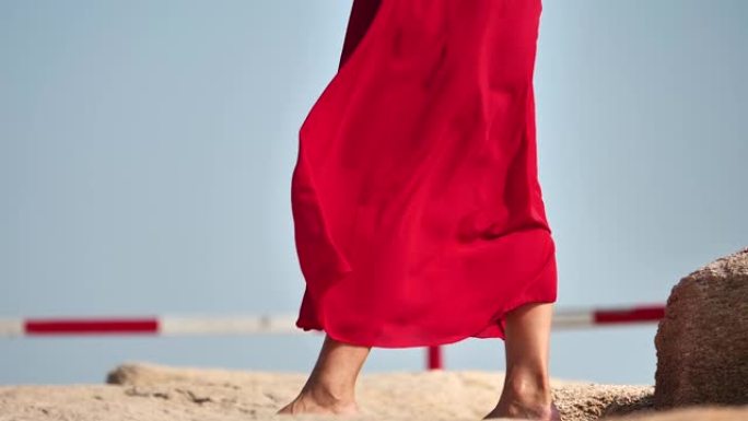 红色连衣裙随风飞翔，赤脚女孩站在岩石上，超级慢动作，浪漫美丽的概念。