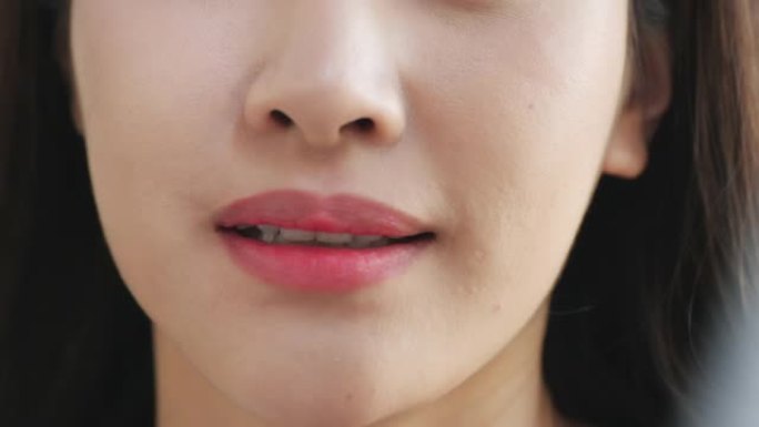 慢动作: 微笑的女人咬着光滑的嘴唇的特写镜头