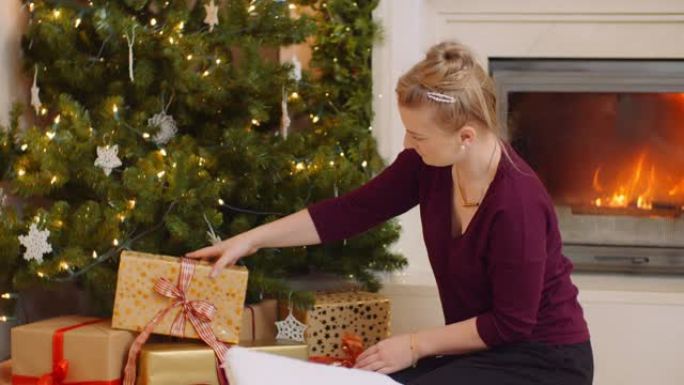 女人拿着礼品盒，在圣诞树下定位