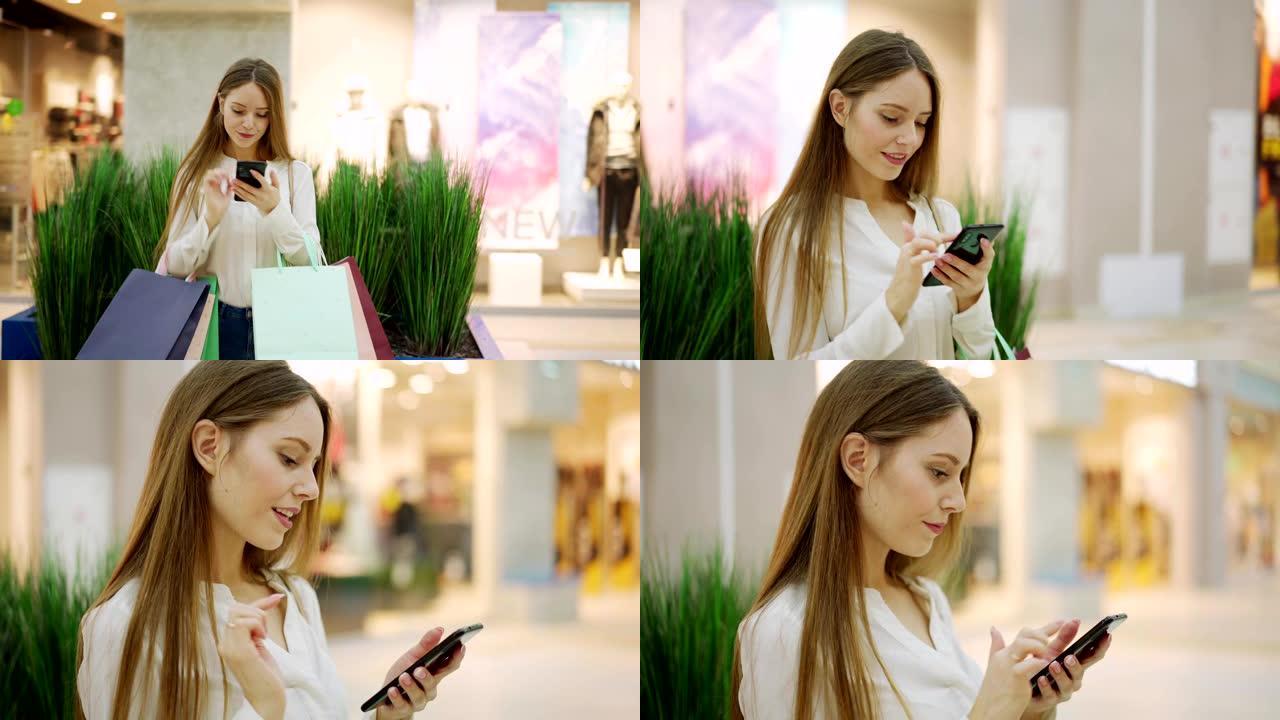 放大美丽的年轻女子站在商场里拿着购物袋，浏览智能手机上的图片或短信的照片
