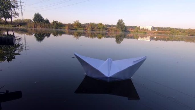 白色的船漂浮在平静的池塘湖光滑的镜面上