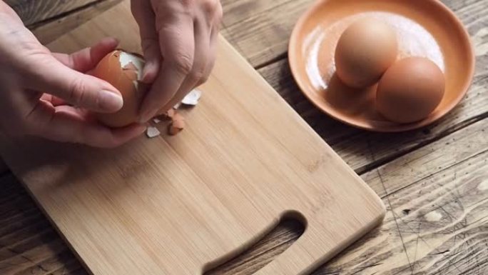 女性双手特写干净煮鸡蛋。家用厨房木桌