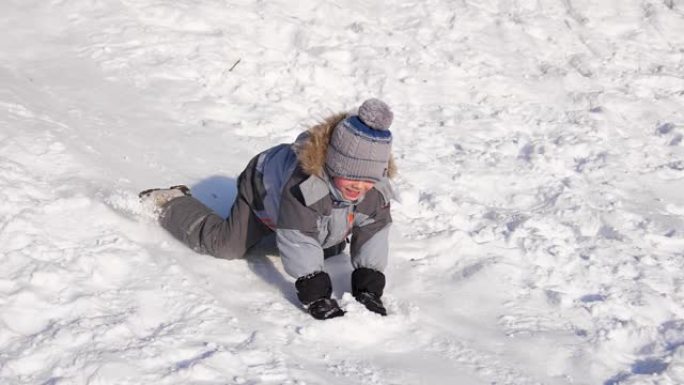 一个孩子在雪山上骑车玩耍。慢动作。白雪皑皑的冬季景观。户外运动