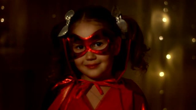 小女孩扮演超级英雄。穿着红色雨衣的有趣婴儿扮演超级英雄。超级英雄和权力概念。肖像特写。选择性聚焦