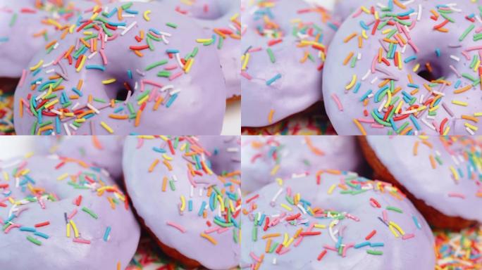 极端特写旋转的彩色糖果覆盖着紫色的糖衣甜甜圈戒指。4k龙红相机