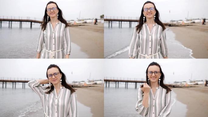 一个穿着长裙的女人在镜头前赤脚在海滩上，微笑着享受生活。