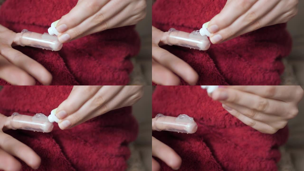 女性手在按摩器牙刷上涂抹口香糖凝胶。出牙概念。慢动作和特写