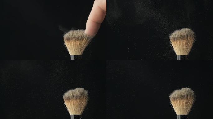女性手指用化妆刷甩掉粉末，使粉末爆炸。慢动作。
