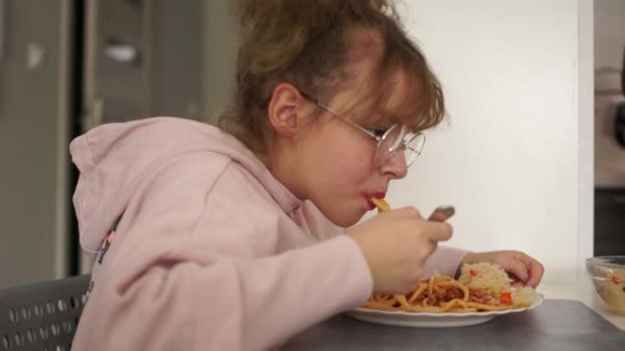 十几岁的女孩在学校食堂吃意大利肉酱。健康饮食女孩戴眼镜