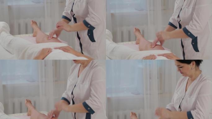 女性按摩治疗师对一个年轻女孩的整个腿部进行按摩