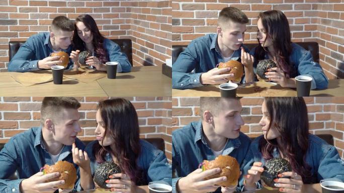 可爱的情侣在咖啡馆里聊天和吃汉堡