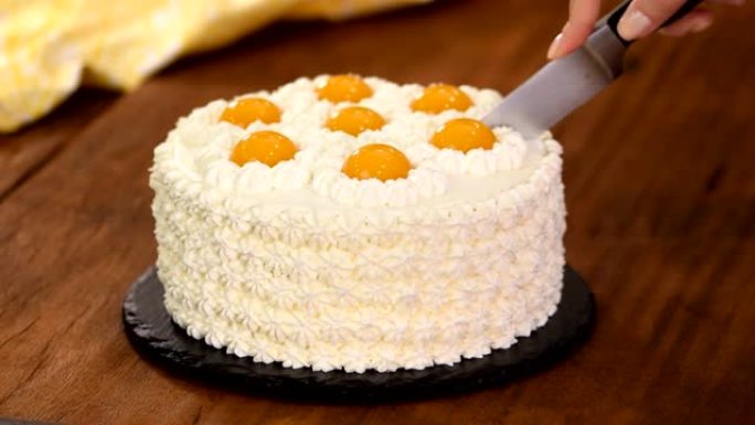 Female hands cutting homemade cream cake with peac