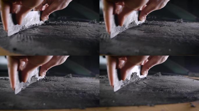 一个男人用工具的手的特写。专业人员在循环的帮助下从粘土中取出表格。生产