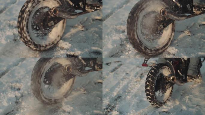 摩托车手在雪地里做轮胎倦怠，慢动作。专业摩托车手在日落时在雪地上漂移并打开摩托车。骑自行车的人在摩托