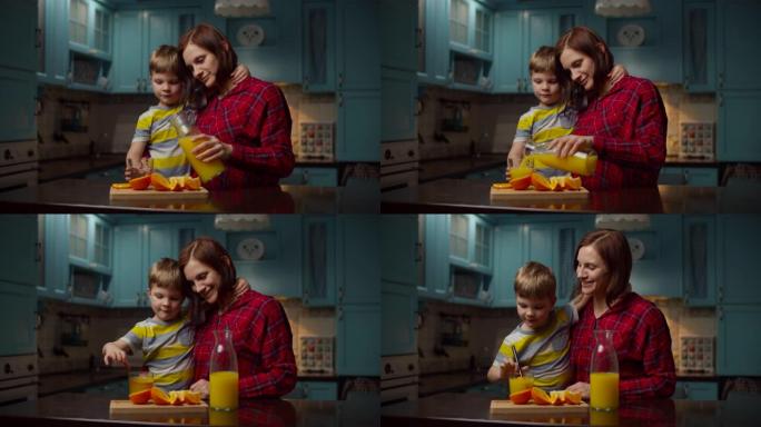 女人把橙汁倒入玻璃里给男孩。30多岁的年轻母子在厨房享受家庭时光。用非塑料吸管喝水果饮料的孩子。
