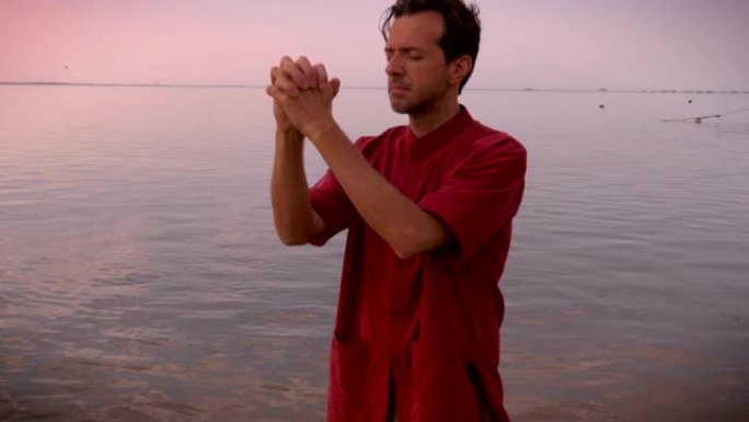 一名男子站在水中祈祷时闭上眼睛的手持镜头