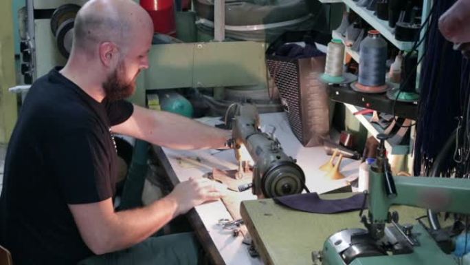 一个用旧缝纫机缝制皮革的男鞋匠。
