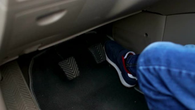 一个小男孩在爸爸的车里踩油门的特写镜头。