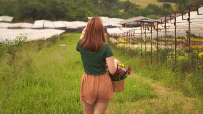 亚洲少女在菊花花场散步，拿着花篮，用手机自拍的肖像
