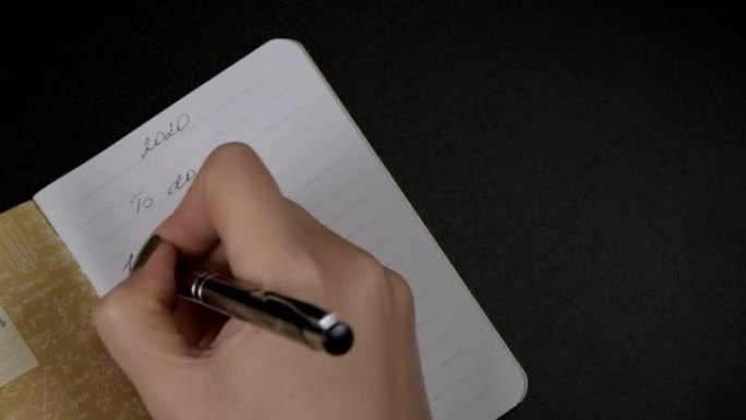 女性双手用铅笔写字在空白条纹笔记本上做列表编号2020，提醒概念。规划2020