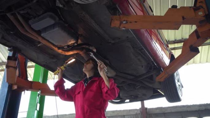 女机械师在修理厂检查车下。