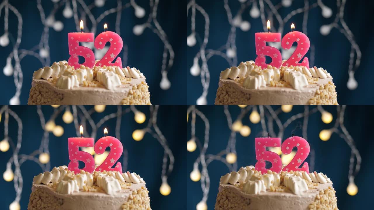蓝色背景上有52个粉色蜡烛的生日蛋糕。蜡烛吹灭了。慢动作和特写视图