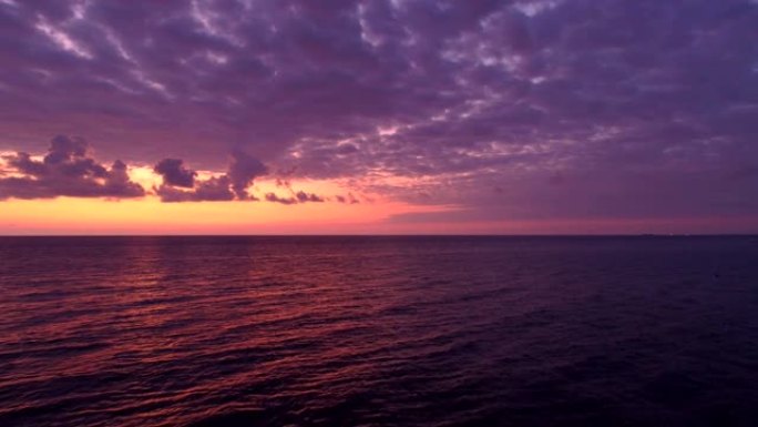 日落时平静的海面上的紫色天空的鸟瞰图