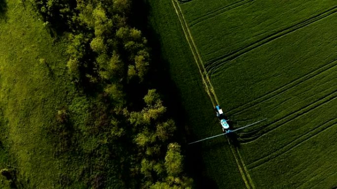 通过特殊安装灌溉绿地的拖拉机的鸟瞰图。用农药喷洒田间生长并防止啮齿动物，寄生虫和害虫的昆虫的过程。