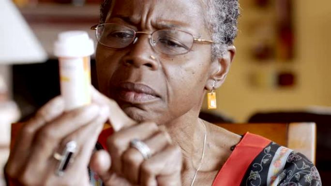 非裔美国高级妇女试图阅读她手中的药瓶标签
