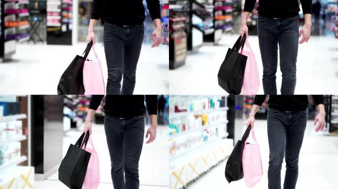 特写，男人的腿走在购物中心，手里拿着购物袋
