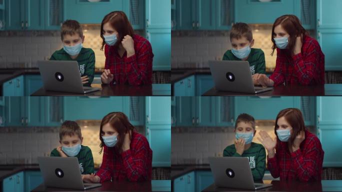 30多岁的母亲和男孩戴着医用口罩看着笔记本电脑屏幕，与亲戚在线交谈，挥手致意。家庭在医疗口罩在家里的