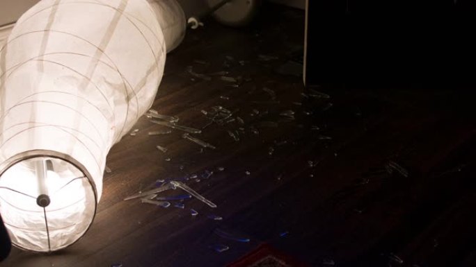 盗窃的房屋破碎的玻璃散落在地板上，带有警车照明