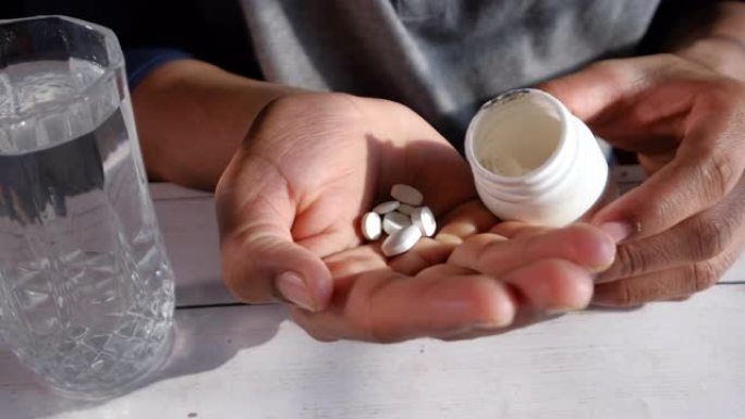 Close up of man pruing pills on palm of hand