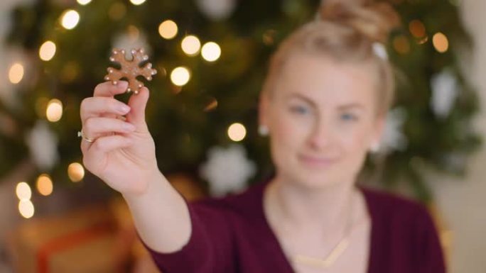 女人在圣诞树上拿着雪花形状的饼干
