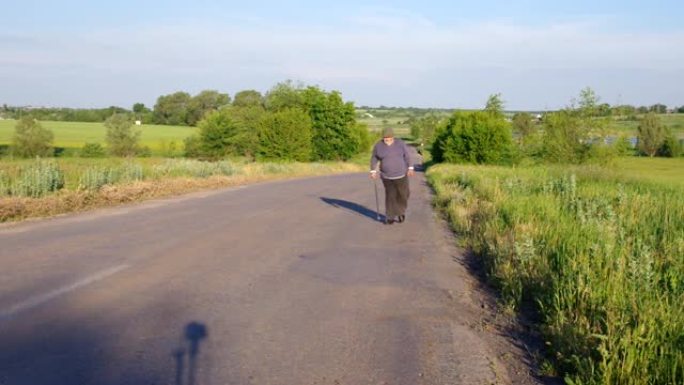 带着手杖的老人走在乡间小路上，带着富有表现力的手势