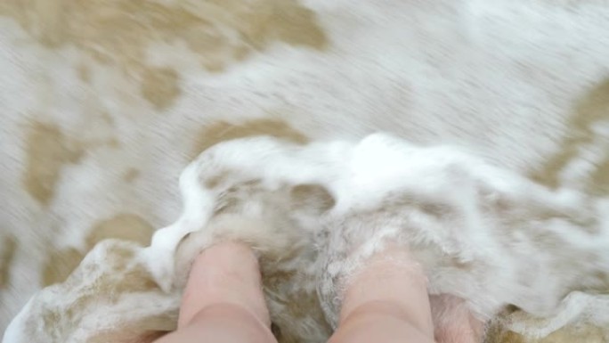 父亲和女儿的腿在海沙海岸上的水浪