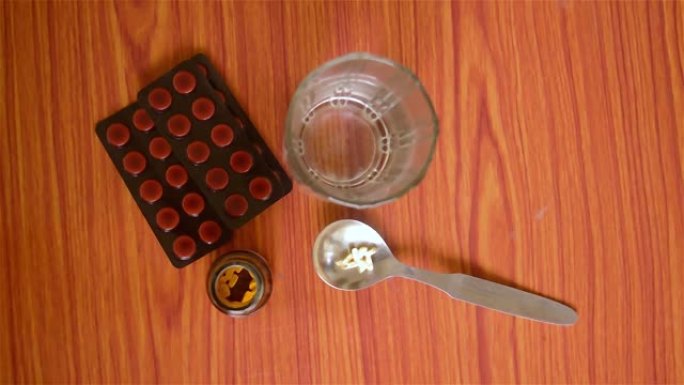 片剂，药丸水泡，一瓶药物，胶囊在量匙，与杯水放在桌子上。医学药学主题。
